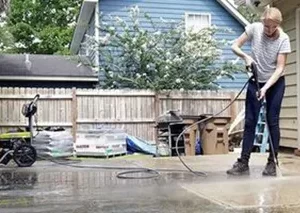 An employee of Herman Home Services in Timonium power washing a driveway.